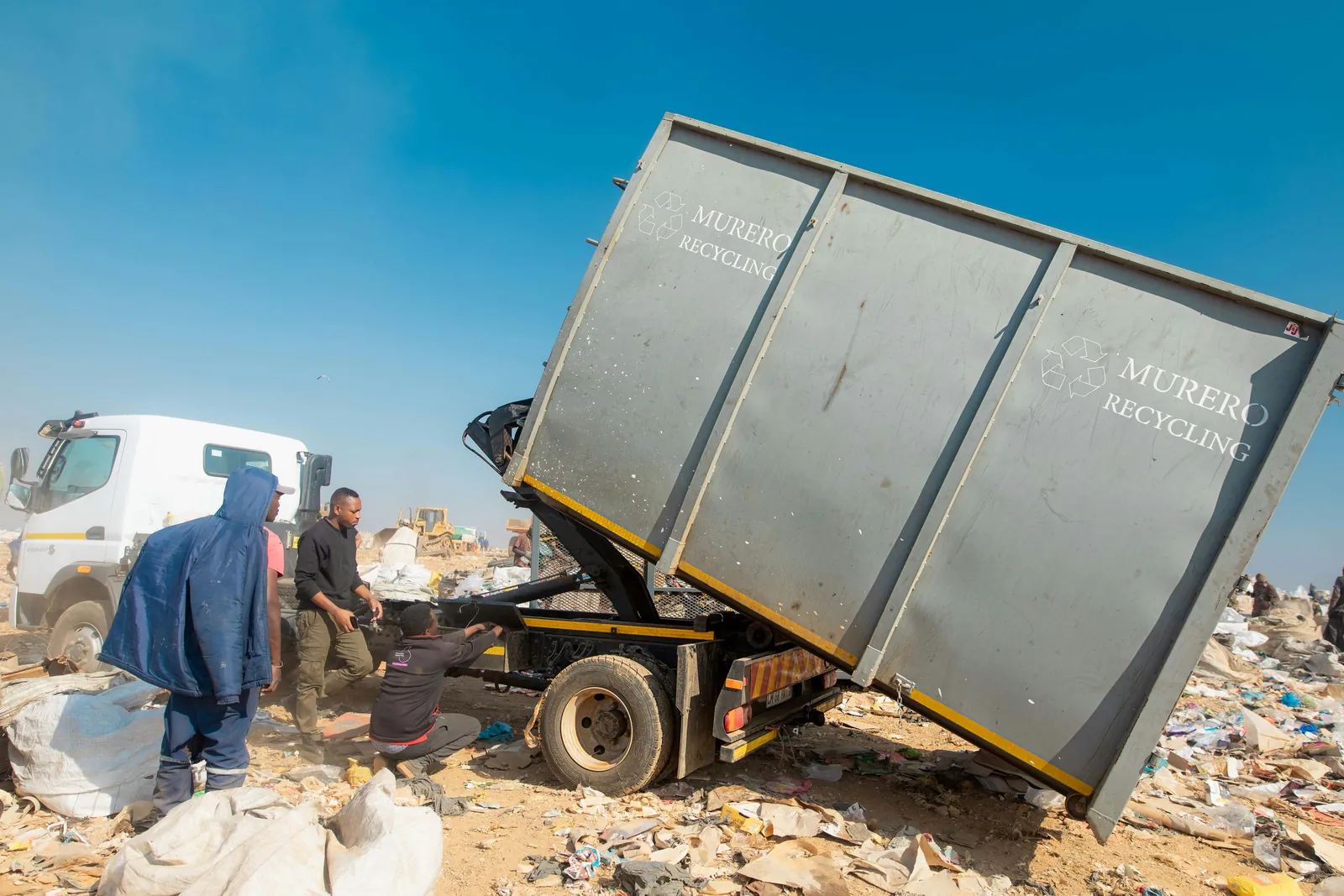 A Murero hook-lift truck tipping a mesh cage at the sorting site.